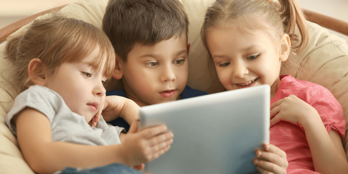 3 small toddlers watching tv on a tablet while laying down in a chair